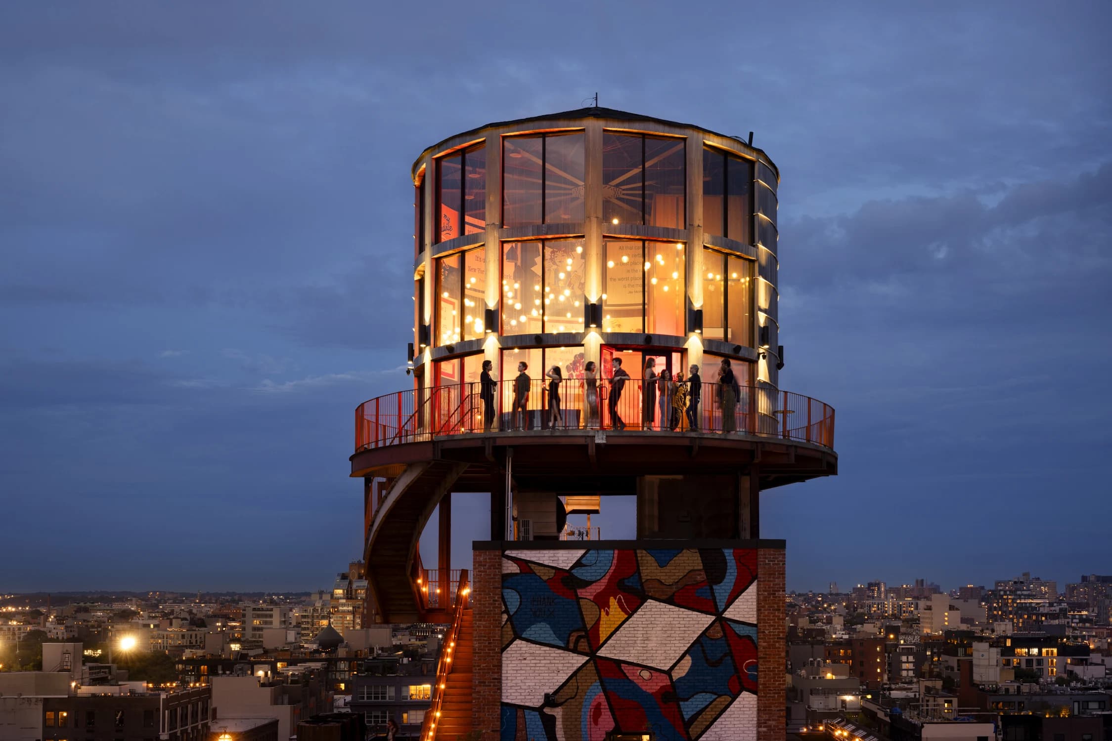 Guests gathering in an illuminated rooftop venue at dusk
