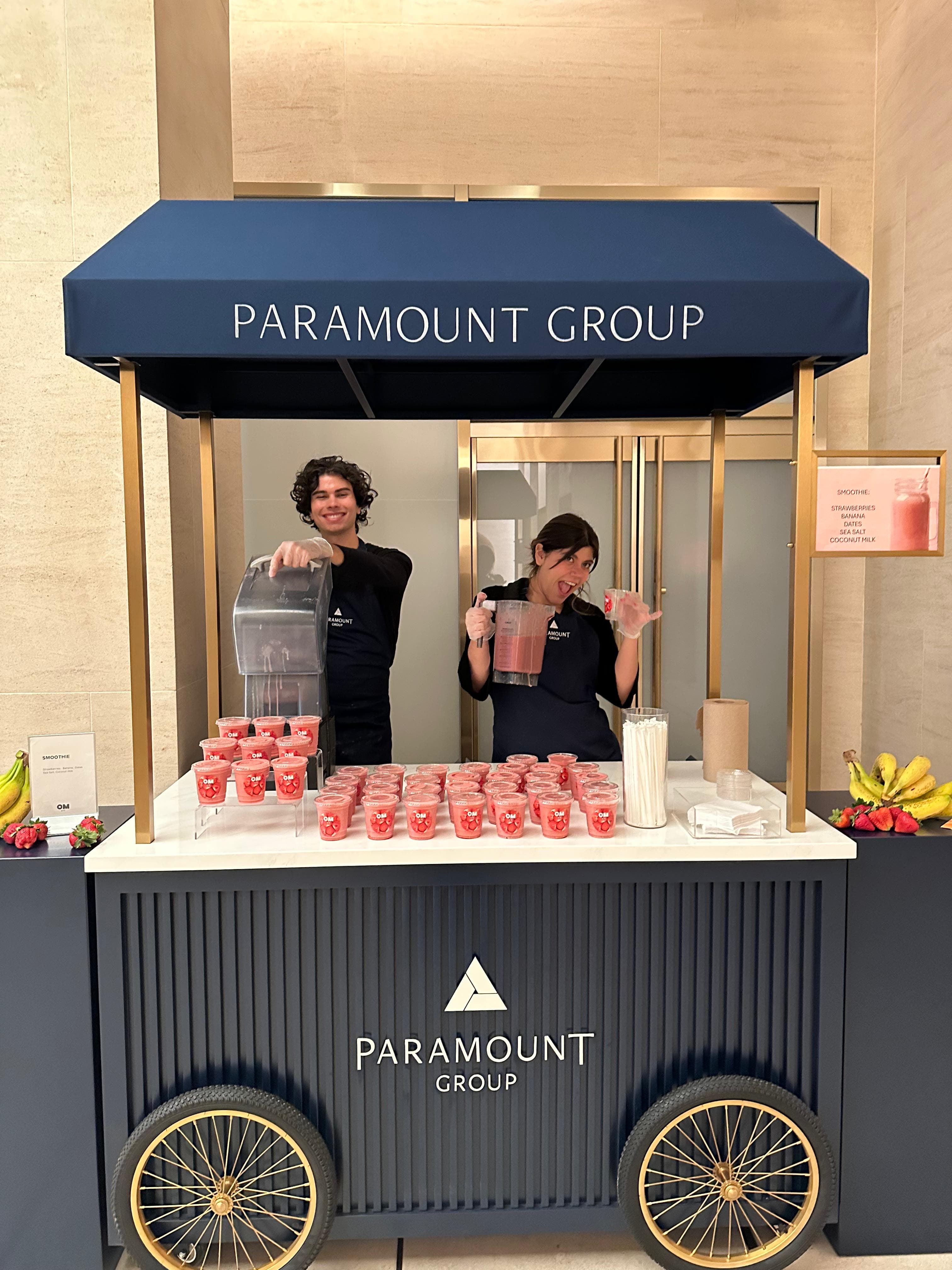 Two attendants serving smoothies from a Paramount Group cart