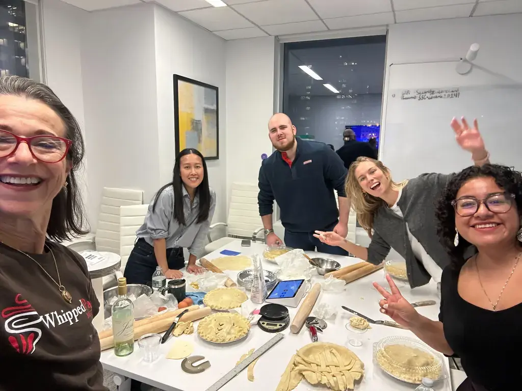 A team smiling during a hands-on pie-making class