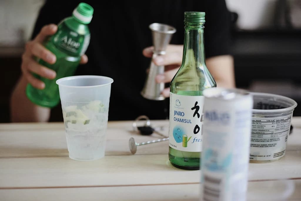 a close up of a glass with lime and ice next to a bottle of alcohol