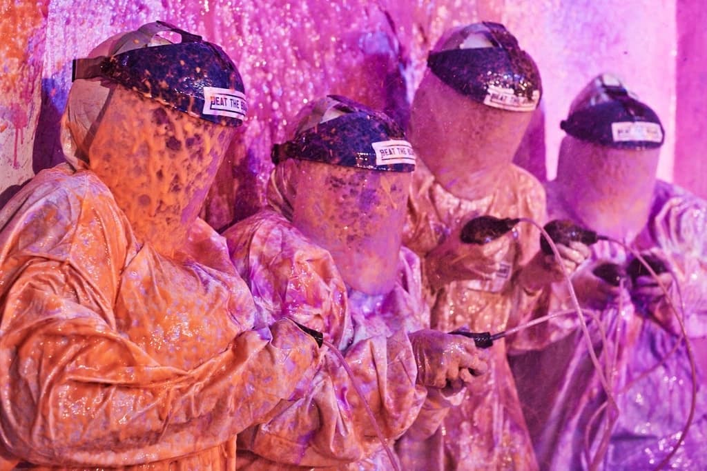 people in white suites with face shields coverd in paint