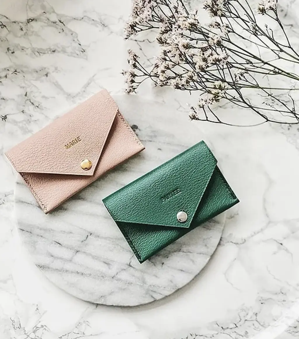 pink and green leather card holders on a marble table