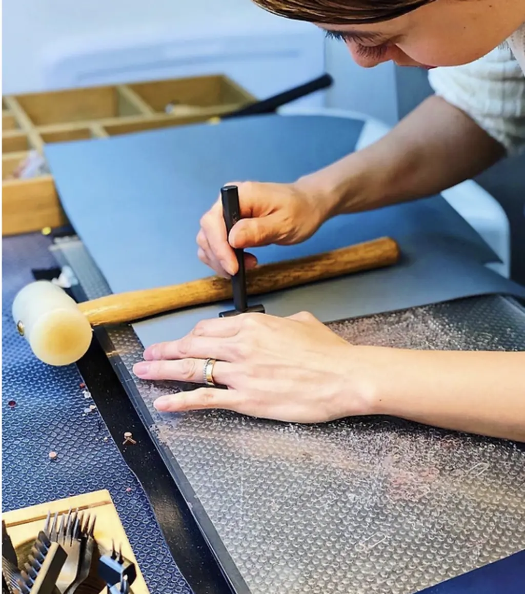 a person wiht a stamp and hammer making a card holder