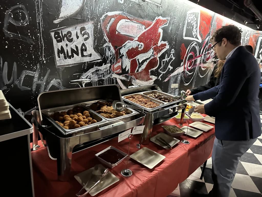 A buffet setup with various dishes in chafing dishes, with people serving themselves.