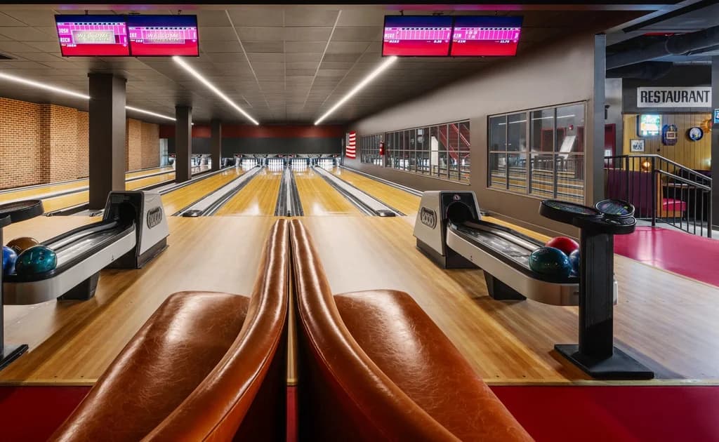Modern bowling alley with multiple lanes, leather seating, and electronic scoreboards, creating a stylish and comfortable environment.