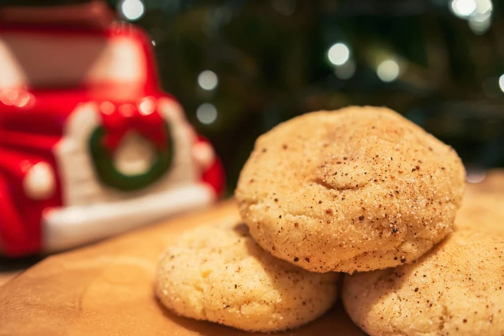 Snickerdoodle cookies stacked on a wooden surface with a festive red truck in the background.