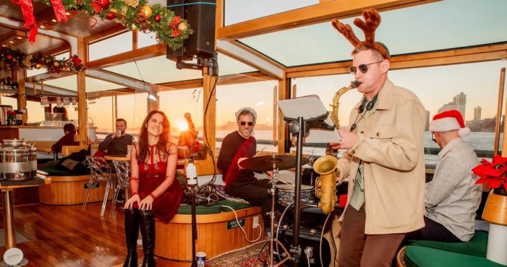 A festive jazz band performing on a boat with holiday decorations and a sunset view.