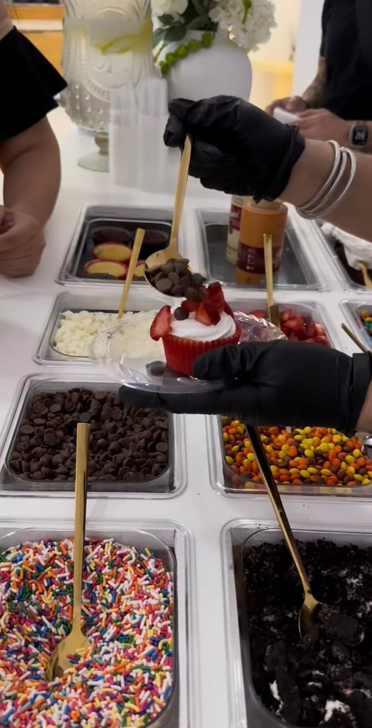Red velvet cupcake topped with whipped frosting, fresh strawberries, and chocolate chips at a build-your-own dessert bar.