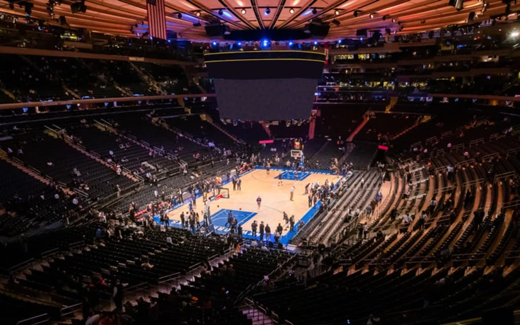 View of Madison Square Garden court during a Knicks game, surrounded by cheering fans.