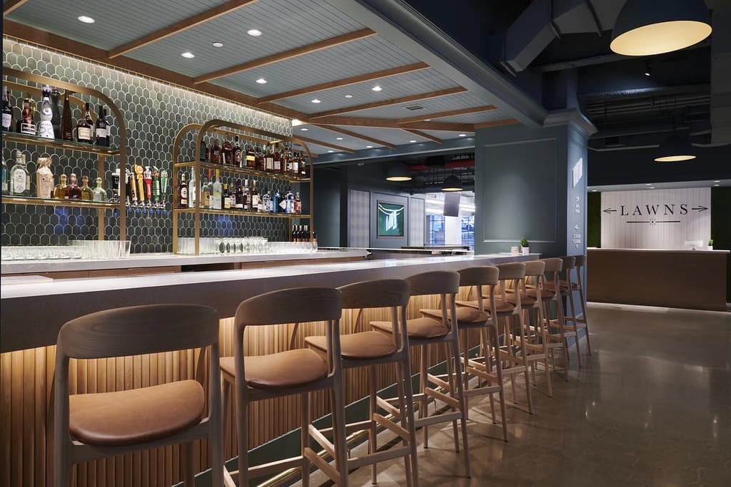 A modern bar area with high stools and a variety of liquor bottles displayed on shelves.