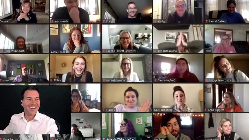 A group of people participating in a virtual meeting, smiling and engaging on a video call.