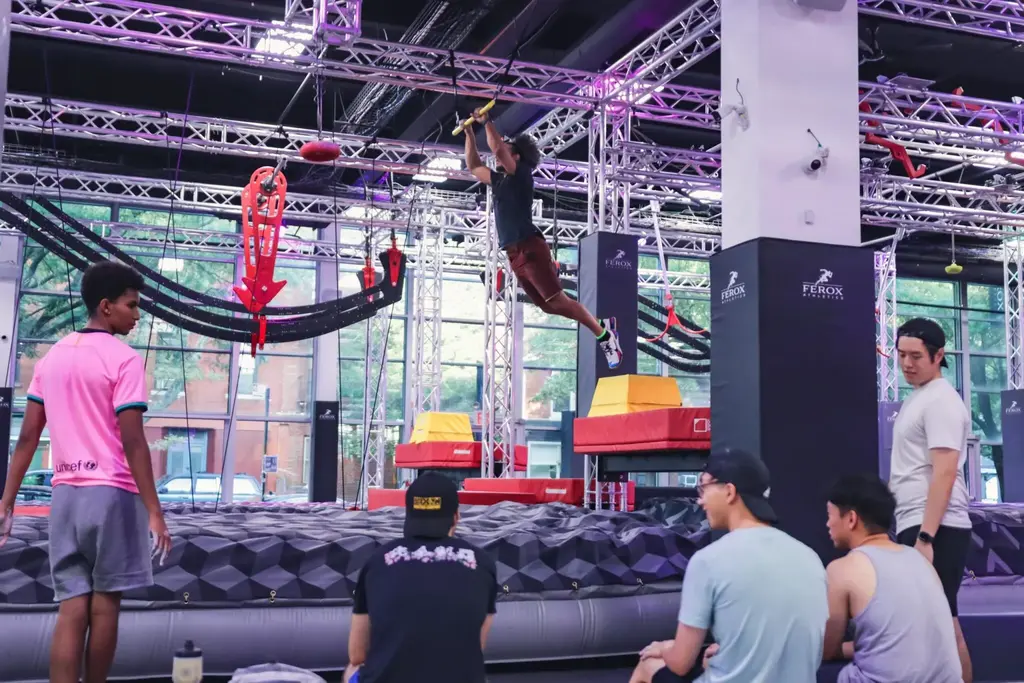 people using a trapeze bar over a foam pit at a ninja park