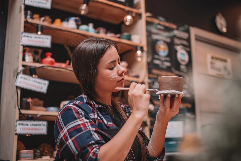 a women painting a handmade pot