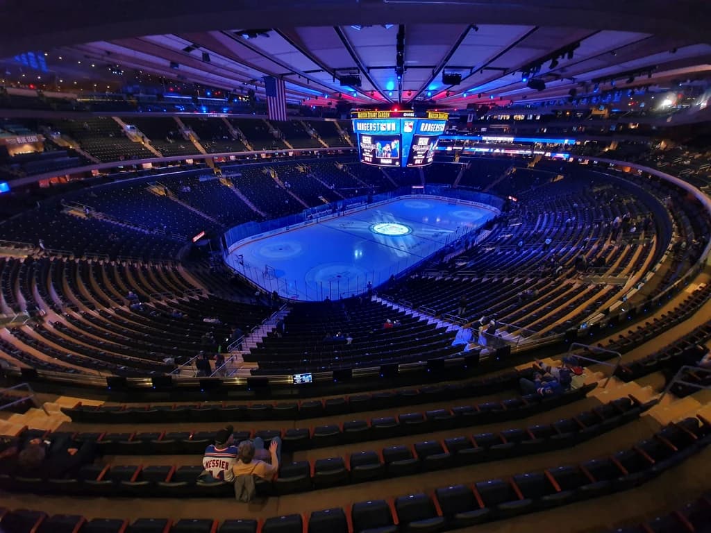 View of Madison Square Garden during a New York Rangers hockey game, showing the ice and the enthusiastic crowd.