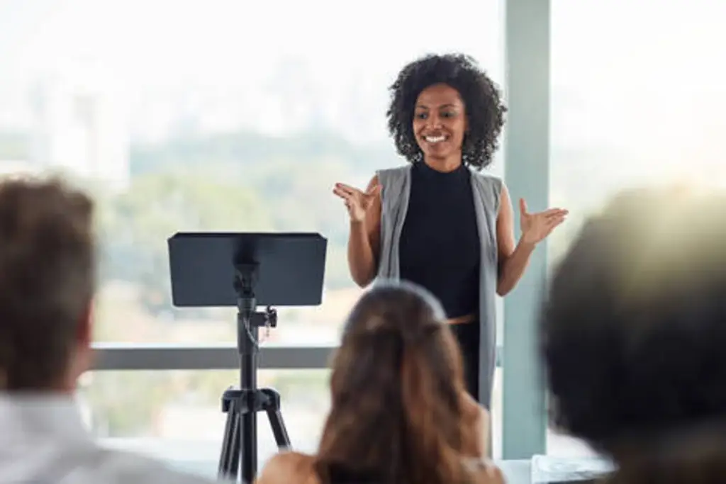 the back of a speaker on stage with an audience in front of them