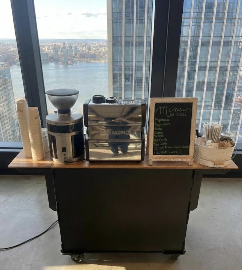 Coffee cart setup with stunning NYC skyline view through floor-to-ceiling windows