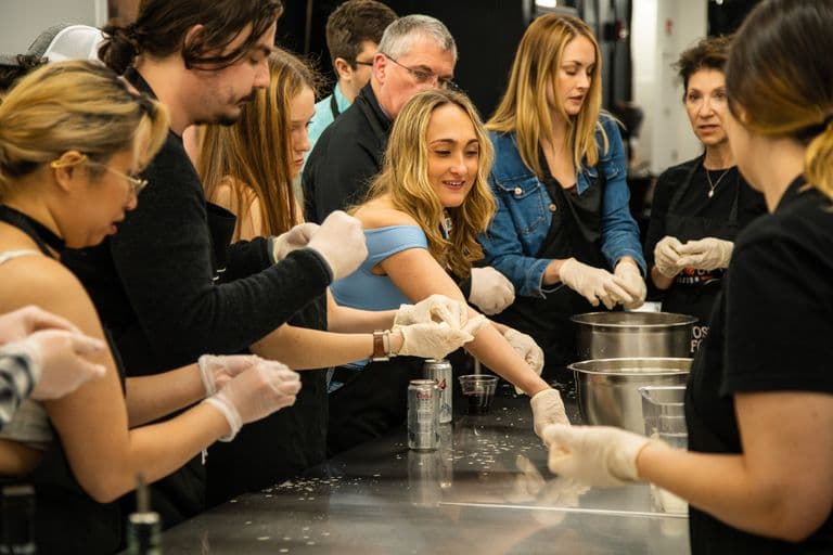Participants in gloves work together at a cooking station during a lively team-building cooking class.