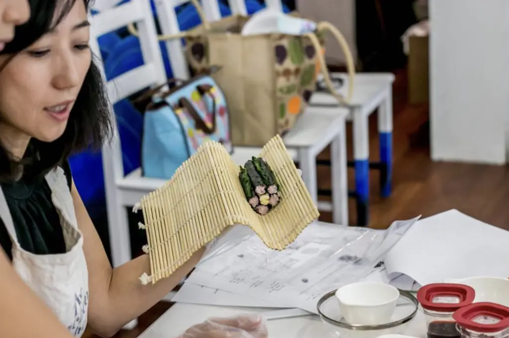 someone holding a sushi in a bamboo mat