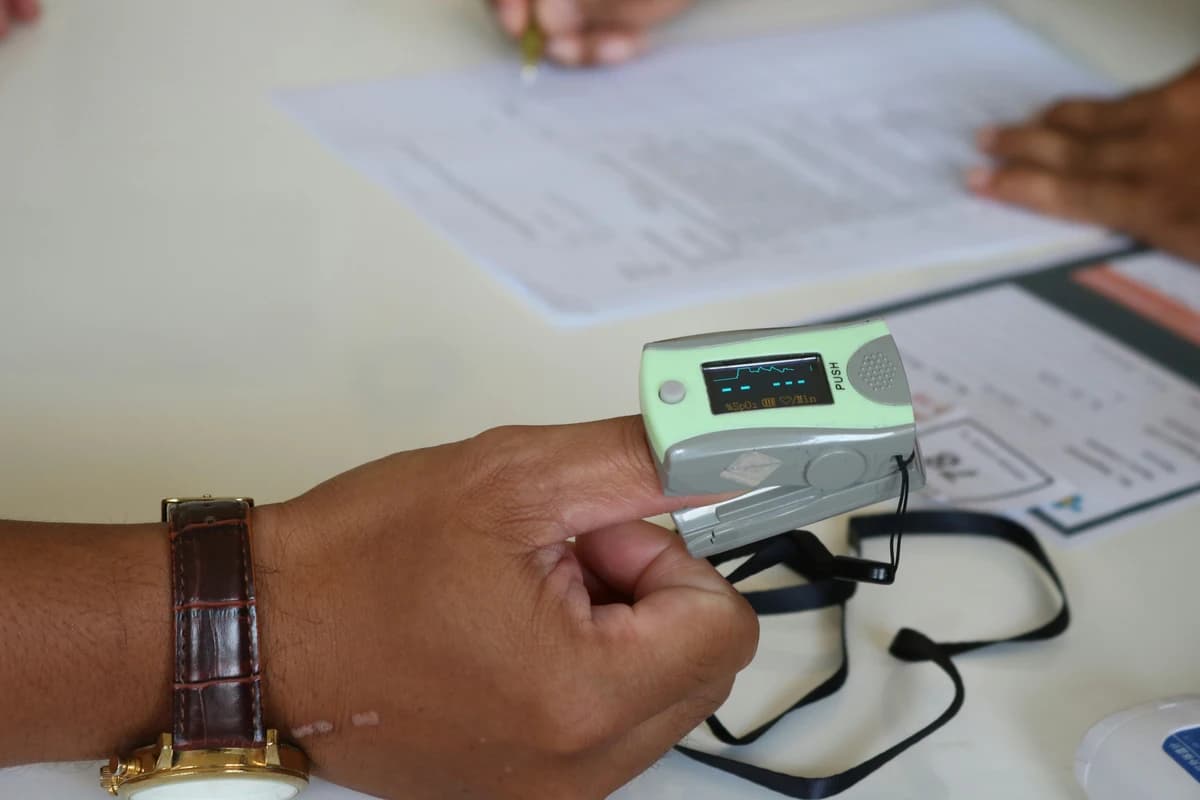 Person wearing a pulse oximeter on their finger while filling out a form.