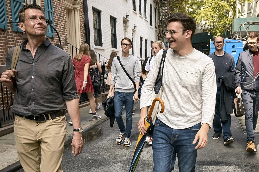 two men walking and talking in front of a group of people