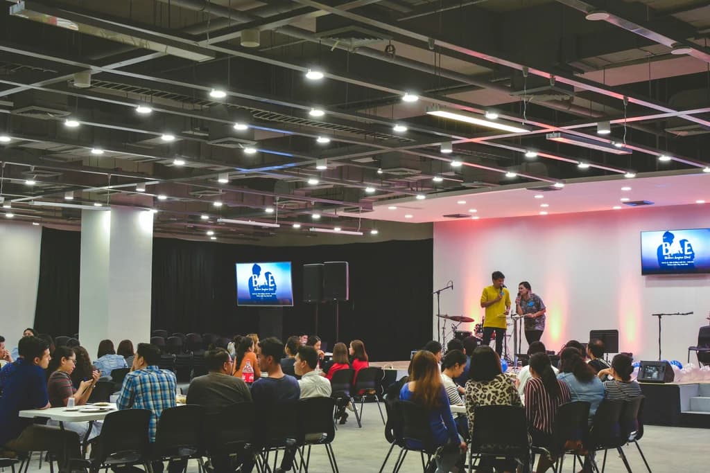 two speakers on a stage infront of a large group