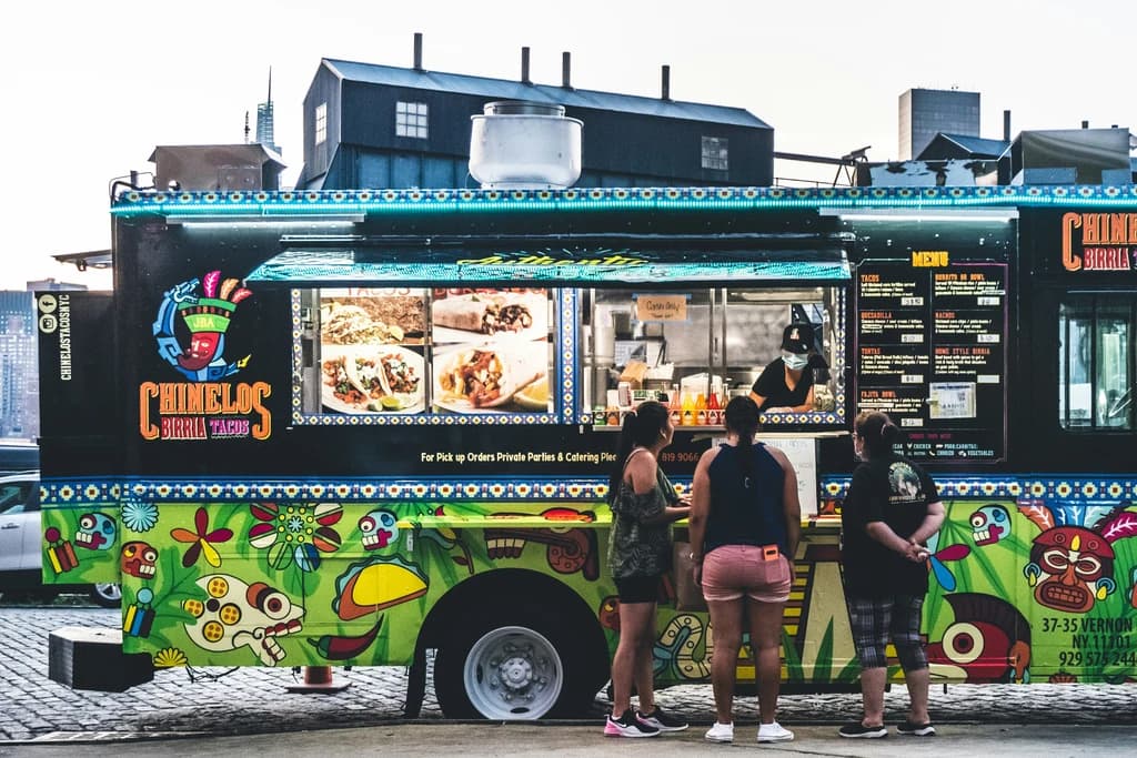 a food truck with people lined up to it