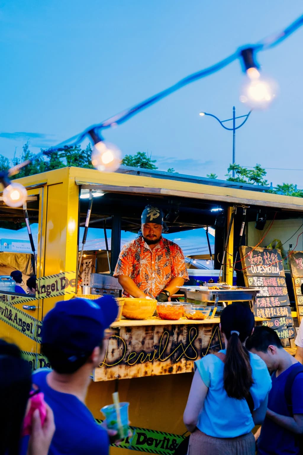 a man standing at a food truck window wiht people outside
