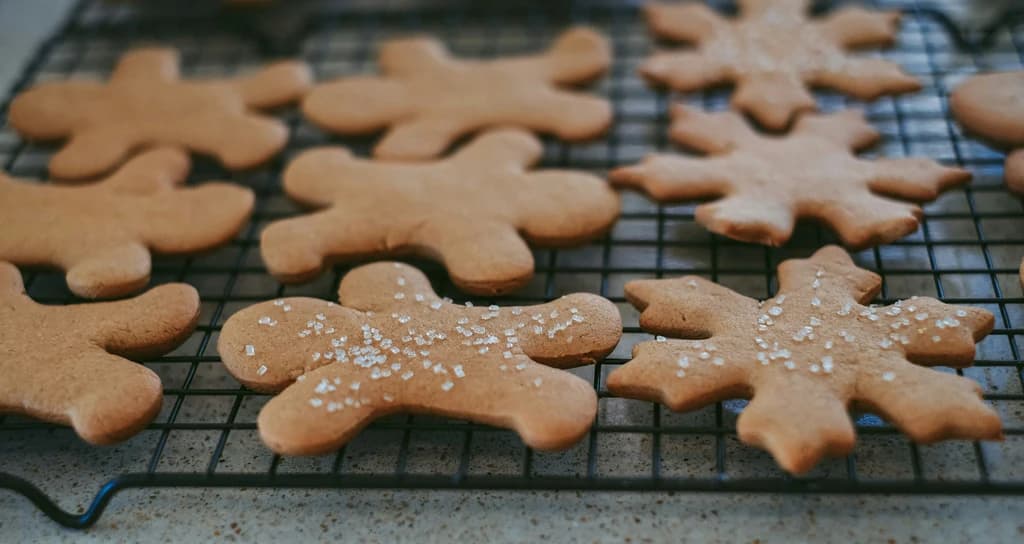 Gingerbread cookies shaped like snowflakes and gingerbread men cooling on a wire rack.