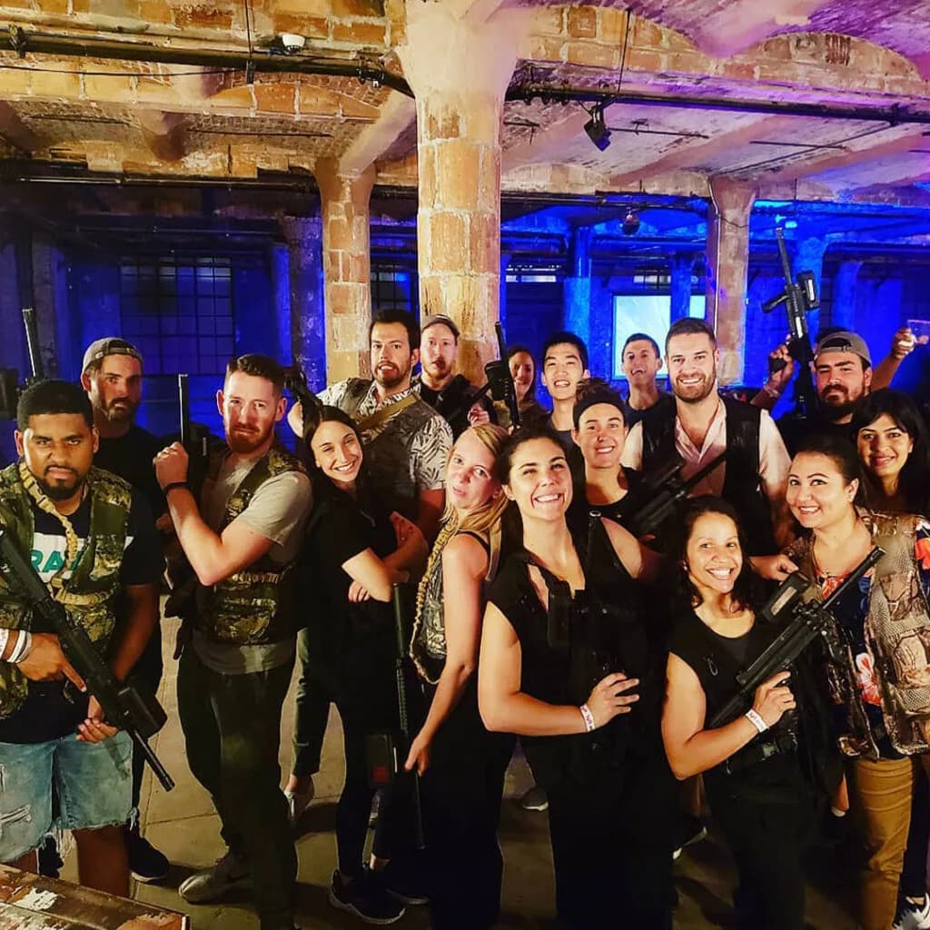 a group of people in laser tag gear smiling at the camera