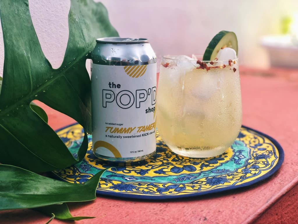 a drink with cucumber and spices, with a can of soda next to it