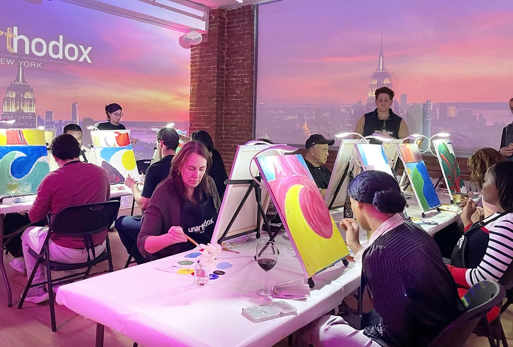 Team members holding large, colorful panels that spell out 'Mighty Northeast' during a collaborative mural painting activity.