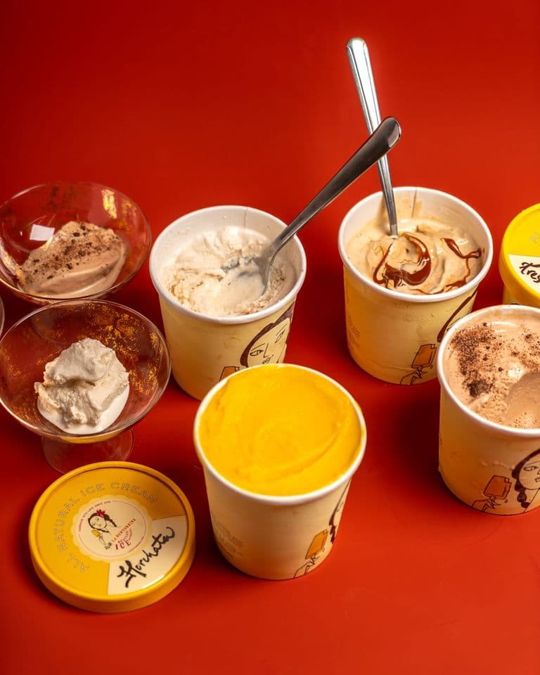 Assorted tubs and bowls of Mexican-inspired ice cream flavors displayed on a bright red background.