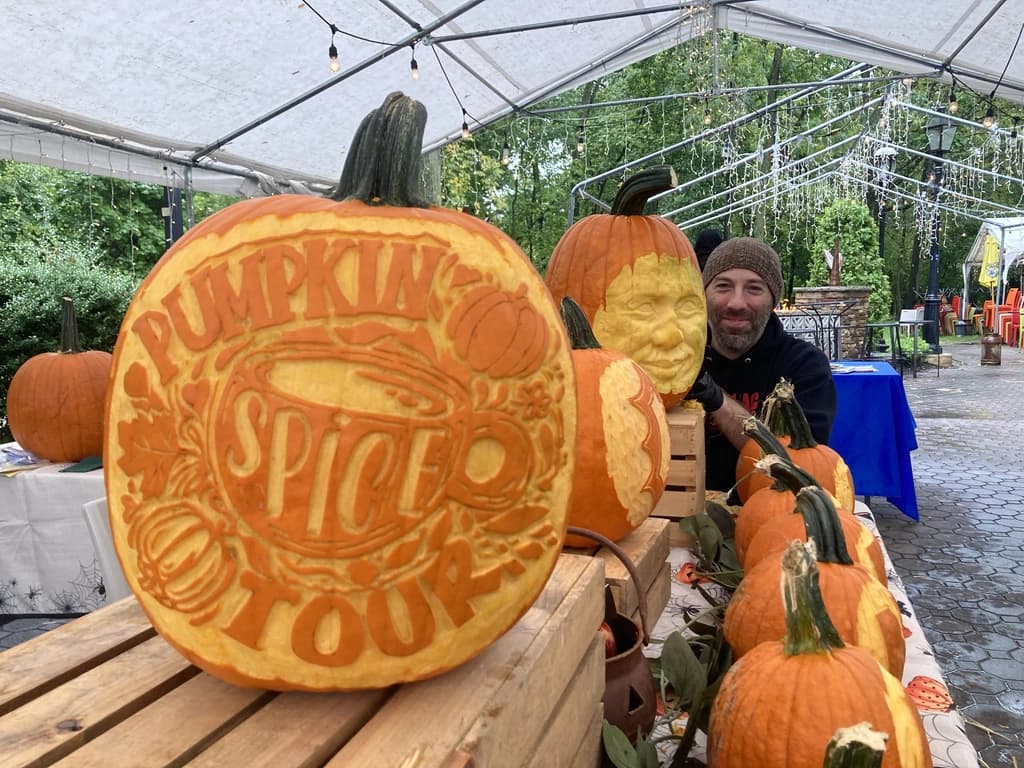 Five carved pumpkins with unique designs glowing from within, placed in a dark setting with candles illuminating them.