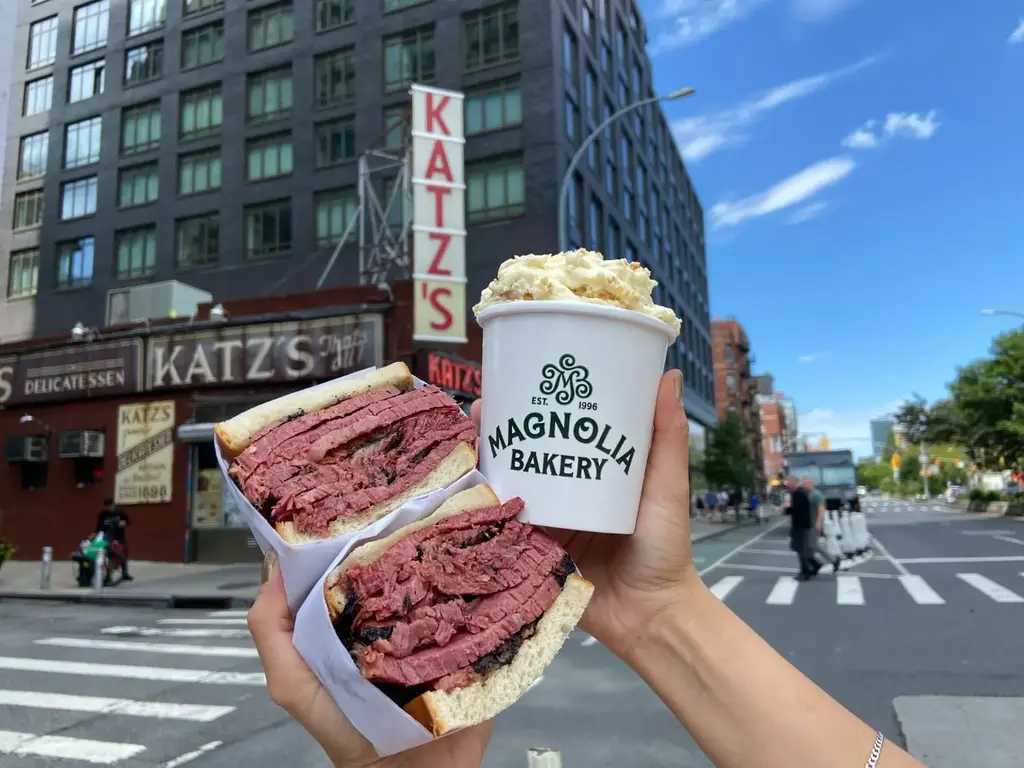 someone holding up a large sandiwch and a cup of mac and cheese
