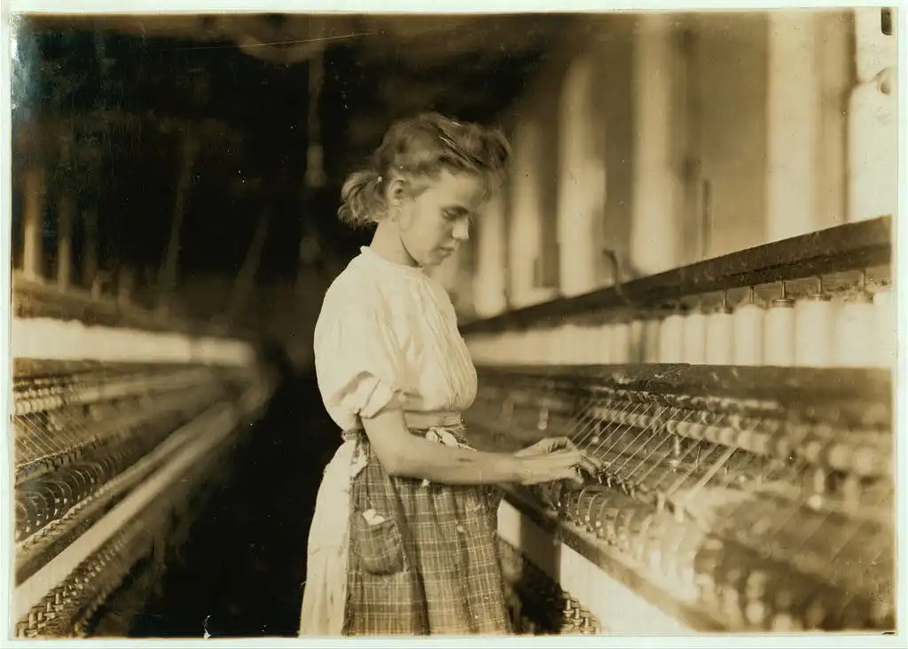 A sepia-toned image of a young girl working at a spinning mill, emphasizing labor conditions in early 20th-century factories.