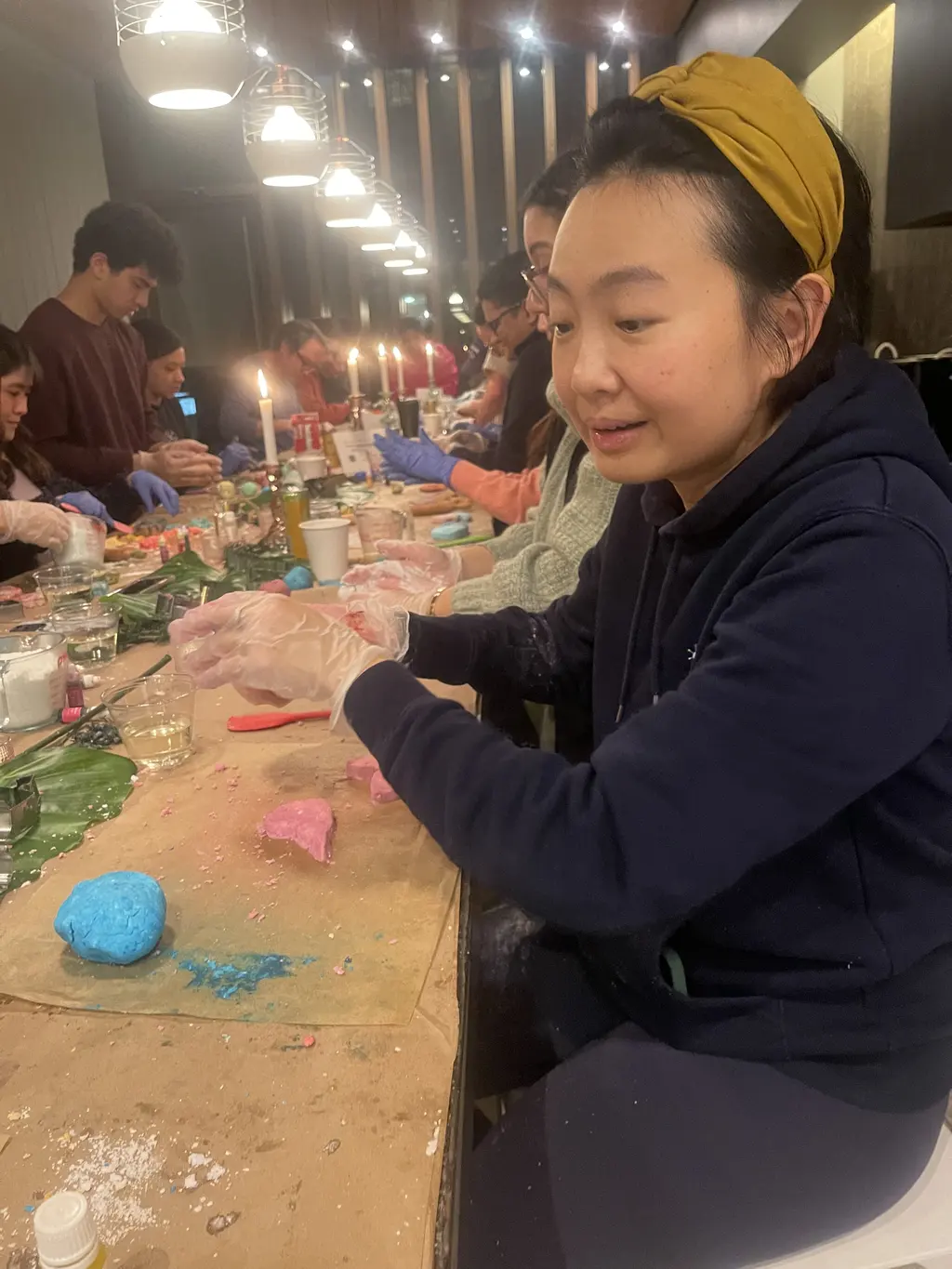 Woman working on products at a display table with candles and supplies