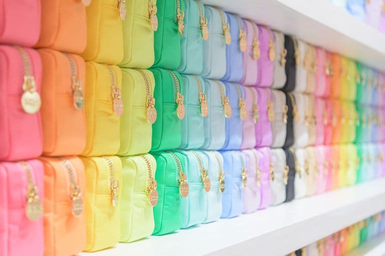 Close-up of neatly arranged Stoney Clover pouches in a vibrant rainbow gradient. Each pouch features a gold zipper with a round charm detail. The display creates a visually striking wall of color, showcasing the brand’s signature palette and attention to organization and aesthetic detail.